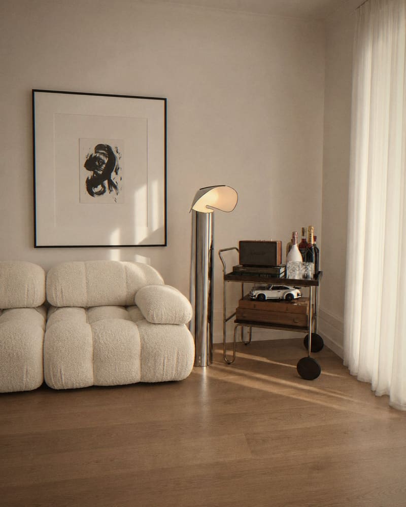 Den with bouclé sofa, chrome lamp and bar cart