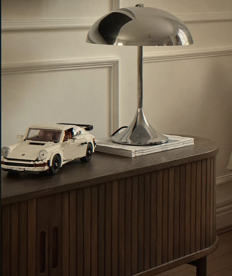 Chrome mushroom table lamp and a model car on a fluted walnut sideboard