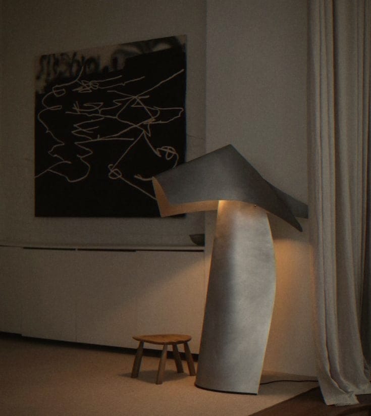 Sculptural floor lamp beside an abstract drawing